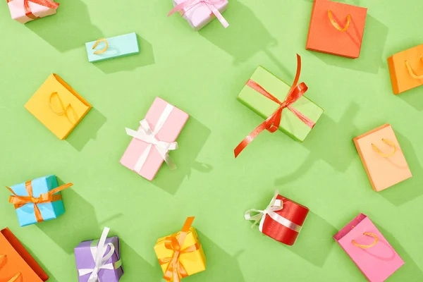 Top view of scattered gift boxes and shopping bags on green background — Stock Photo