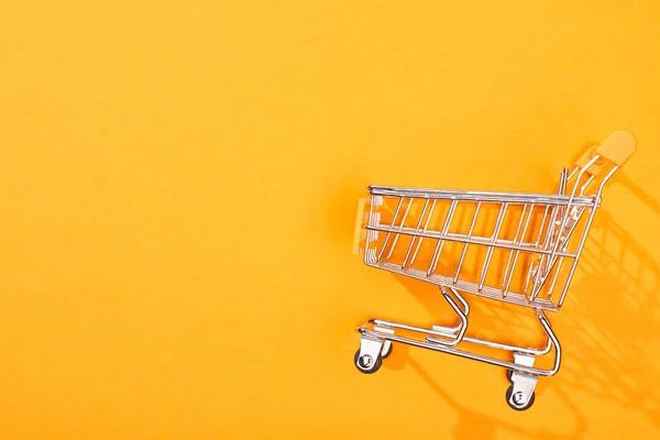 Vista superior do carrinho de compras vazio no fundo laranja brilhante — Fotografia de Stock