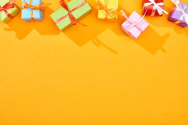 Vista superior de regalos envueltos festivos sobre fondo naranja brillante - foto de stock