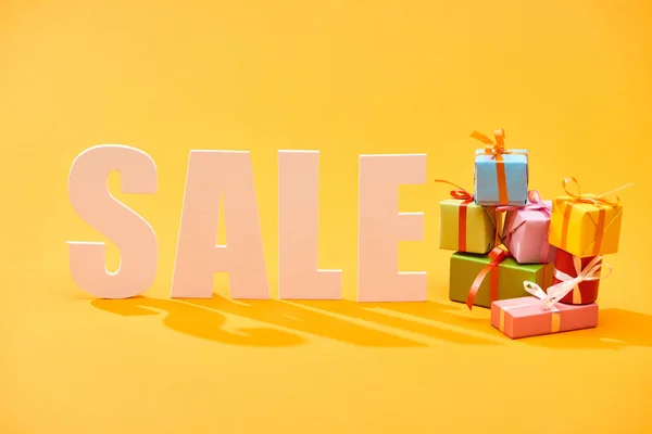 Белая распродажа буквы с праздничными завернутые подарки на ярко-оранжевом фоне — стоковое фото