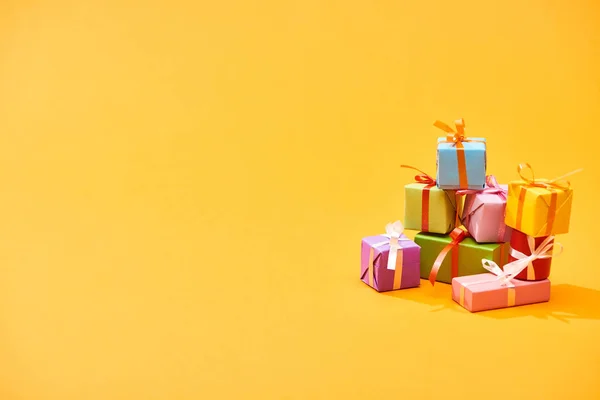 Pilha de caixas festivas coloridas no fundo laranja brilhante — Fotografia de Stock