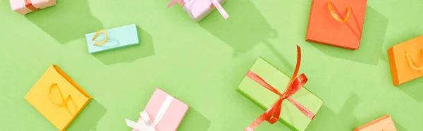Панорамний знімок розкиданих подарункових коробок і сумки для покупок на зеленому фоні — стокове фото