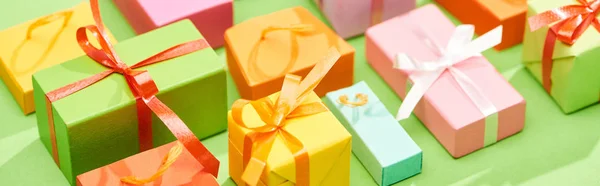 Selective focus of decorative colorful gift boxes on green background, panoramic shot — Stock Photo