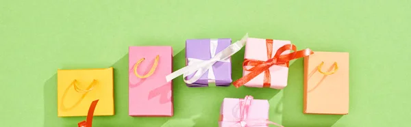 Вид зверху барвисті подарункові коробки та сумки для покупок на зеленому фоні, панорамний знімок — стокове фото
