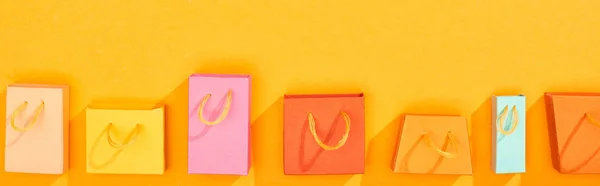 Top view of shopping bags on bright orange background, panoramic shot — Stock Photo