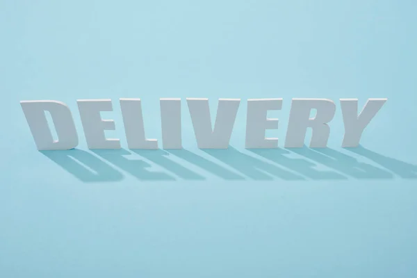 White delivery inscription with shadows on blue background — Stock Photo