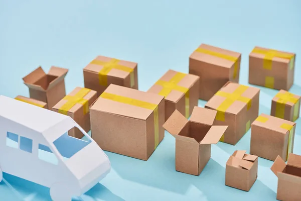 Cardboard boxes near van model on blue background with copy space — Stock Photo