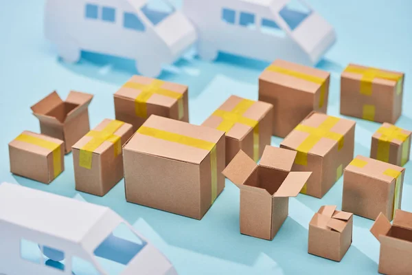 Cardboard boxes near white vans on blue background with copy space — Stock Photo