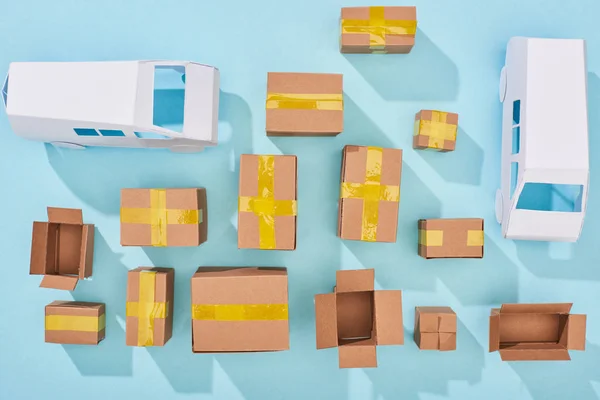 Top view of cardboard boxes and white vans on blue background — Stock Photo