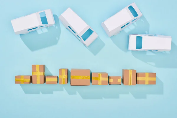 Вид зверху закритих картонних коробок біля фургонів на синьому фоні з місцем для тексту — стокове фото