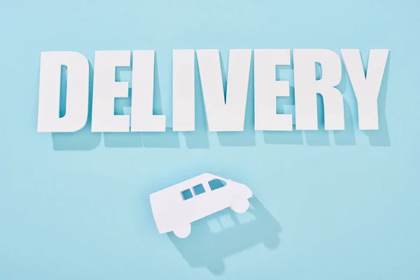 Inscripción de entrega blanca con sombra sobre mini furgoneta sobre fondo azul - foto de stock