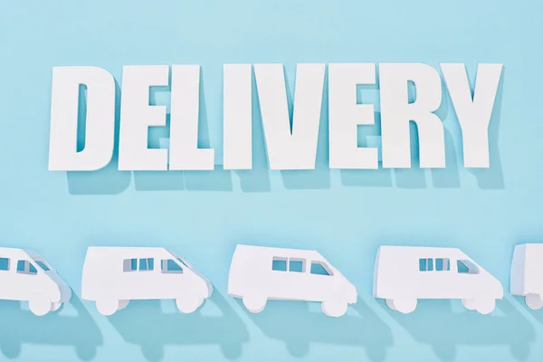 White delivery inscription with shadow above mini vans on blue background — Stock Photo