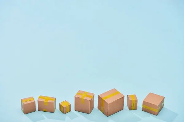 Мініатюрні закриті картонні коробки на синьому фоні з копіювальним простором — стокове фото
