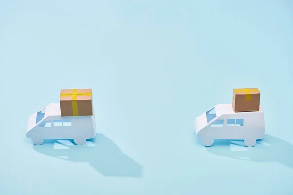 Mini furgoni bianchi con pacchi di cartone su sfondo blu — Foto stock