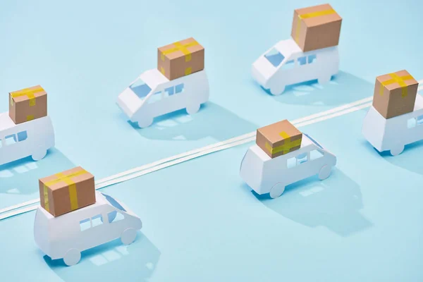 Geschlossene Papppakete auf weißen Kleintransportern auf blauem Hintergrund mit doppelter Linie — Stockfoto