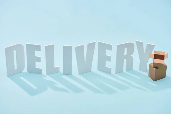 Cardboard boxes one on each other near white delivery inscription on blue background — Stock Photo