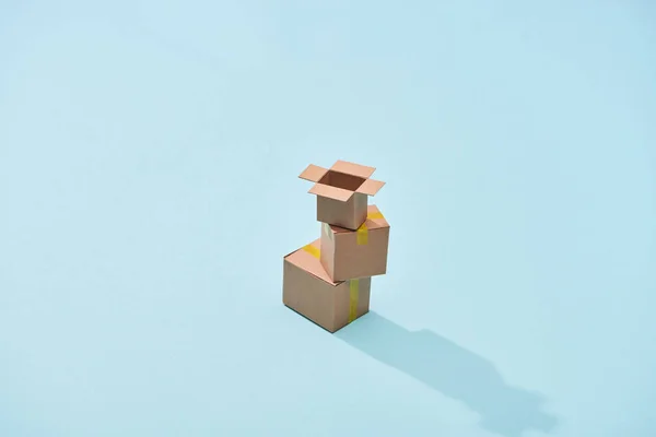 Мініатюрні картонні коробки на синьому фоні з копіювальним простором — стокове фото