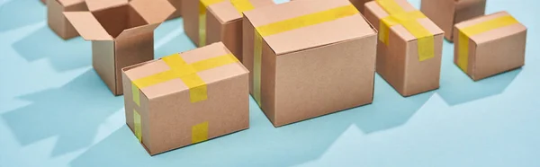 Panoramic shot of cardboard postal boxes on blue background — Stock Photo