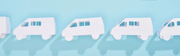 Panoramic shot of miniature white trucks on blue background — Stock Photo