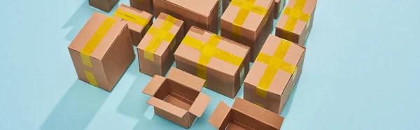 Panoramic shot of miniature carton boxes on blue background — Stock Photo