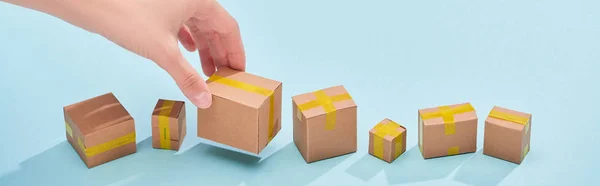 Panoramic shot of woman holding miniature postal box on blue background — Stock Photo