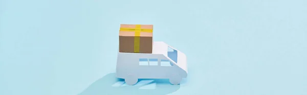 Panoramic shot of mini truck with cardboard parcel on blue background — Stock Photo