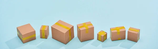 Panoramic view of miniature closed boxes on blue background with copy space — Stock Photo