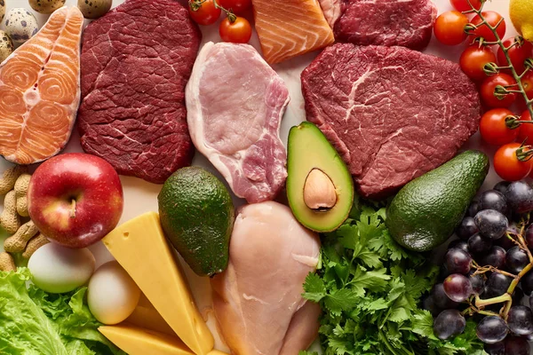 Top view of assorted raw meat, poultry, fish, eggs, vegetables, fruits, nuts, greenery and cheese — Stock Photo