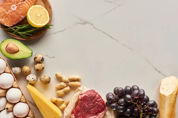 Ansicht von rohem Fleisch und Fisch mit Avocado, Zitrone, Käse, Eiern, Trauben, Erdnüssen und Baguette — Stockfoto