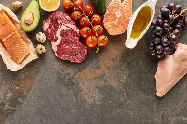 Ansicht von rohem Fleisch, Fisch und Geflügel in der Nähe von Gemüse, Obst, Eiern und Olivenöl auf Marmoroberfläche mit Kopierraum — Stockfoto