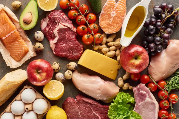 Vista superior de carne variada, aves de corral, pescado, huevos, frutas, verduras, queso, aceite de oliva y baguette - foto de stock