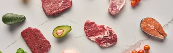 Panoramic shot of raw meat and salmon steaks near avocados and tomatoes — Stock Photo