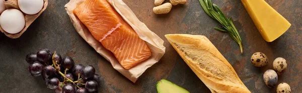 Panoramic shot of raw salmon with eggs, cheese, grape, baguette and rosemary twig on marble surface — Stock Photo