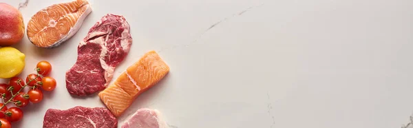 Foto panorámica de carne cruda, pescado y aves de corral cerca de tomates, limón y manzana en la superficie de mármol con espacio para copiar - foto de stock