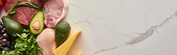 Panoramic shot of raw meat and poultry fillet with avocados, cheese and greenery on marble surface with copy space — Stock Photo