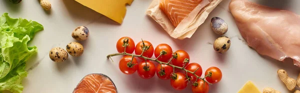 Foto panorámica de rama de tomates cherry, huevos de codorniz, lechuga, aves de corral crudas y pescado sobre superficie de mármol - foto de stock