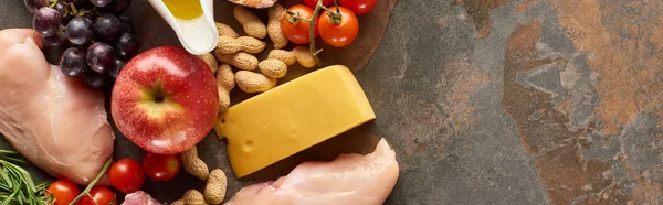 Panoramic shot of raw poultry fillet with fruits, peanuts, tomatoes, cheese on marble surface — Stock Photo