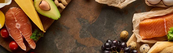 Tiro panorâmico de salmão cru com queijo, legumes, ovos de codorna, amendoim em tábuas de corte de madeira na superfície de mármore — Fotografia de Stock