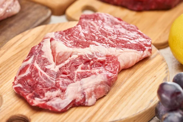 Vista de perto da carne crua na placa de corte de madeira leve — Fotografia de Stock