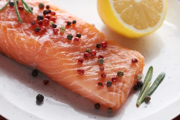 Vue rapprochée du saumon frais cru au poivre, citron et romarin — Photo de stock