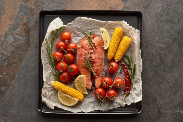 Top view of raw salmon with vegetables, lemon and rosemary in oven tray — Stock Photo