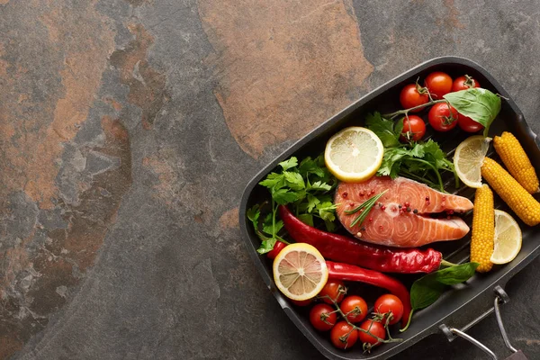 Vista superior del salmón sin cocer con verduras, limón y hierbas en la sartén - foto de stock