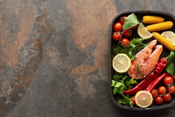 Vue du dessus du saumon frais cru aux légumes, au citron et aux herbes dans une poêle à griller — Photo de stock