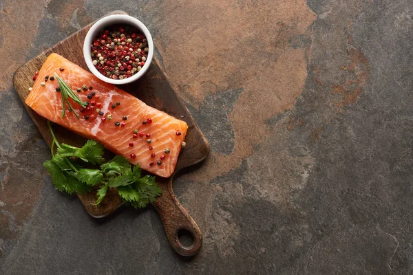 Top view of raw fresh salmon with peppercorns, parsley on wooden cutting board — Stock Photo