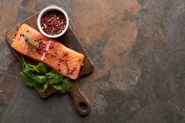 Vista dall'alto di salmone fresco crudo con grani di pepe, prezzemolo sul tagliere di legno — Foto stock