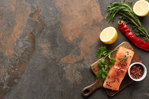 Top view of raw salmon with greenery and lemon on wooden cutting board — Stock Photo