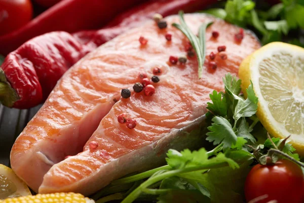 Close up view of raw salmon steak with spices, vegetables and greenery — Stock Photo