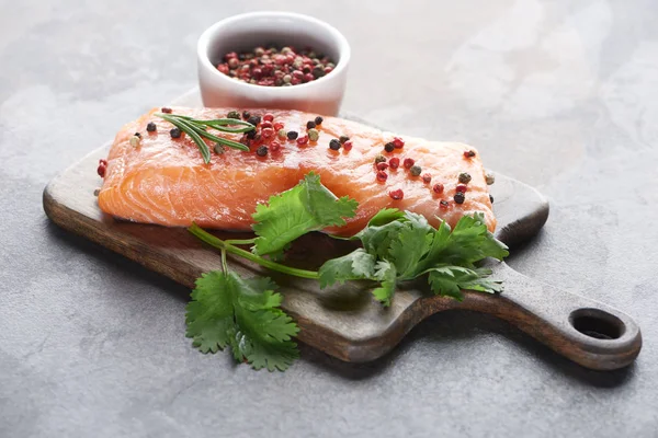 Raw fresh salmon with peppercorns, parsley and rosemary on wooden cutting board — Stock Photo