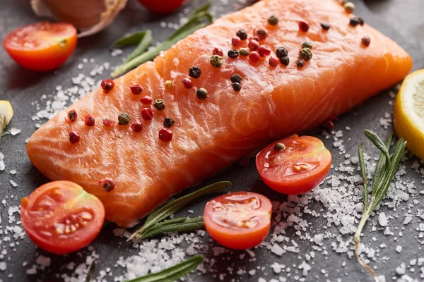 Raw salmon with salt and tomatoes on stone board — Stock Photo
