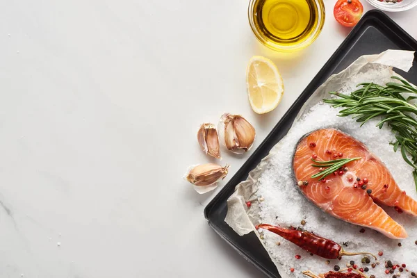 Vista superior de filete de salmón sin cocer con limón, romero y chiles en bandeja del horno con sal - foto de stock